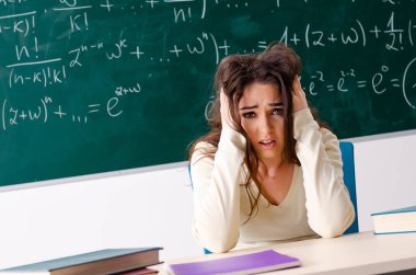 Karatahtanın önünde genç bayan matematik öğretmeni.  