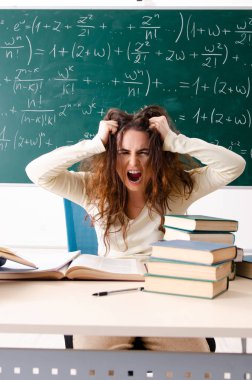 Karatahtanın önünde genç bayan matematik öğretmeni.  