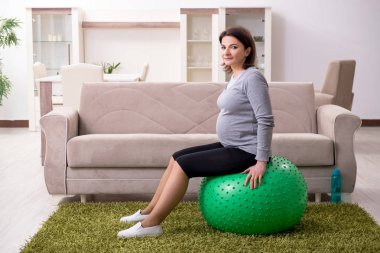 Evde egzersiz yapan yaşlı hamile bir kadın. 