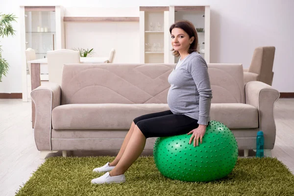 Verouderde zwangere vrouw doet oefeningen thuis — Stockfoto