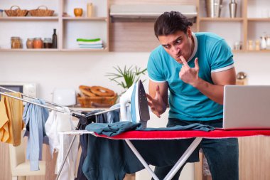 Genç adam evde çamaşır ütülüyor. 