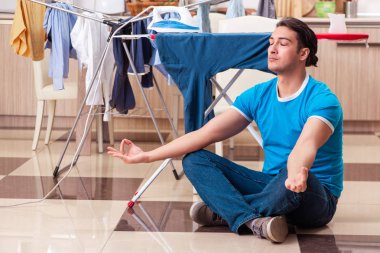 Genç adam evde çamaşır ütülüyor. 