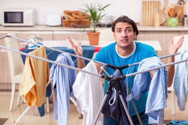 Genç adam evde çamaşır ütülüyor. 