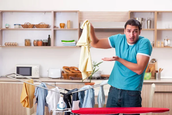 Genç adam evde çamaşır ütülüyor. 