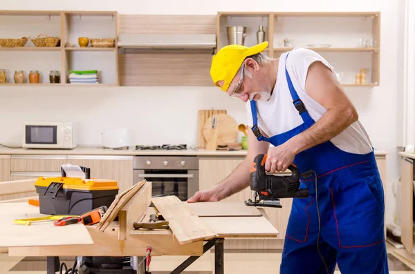 Пожилой подрядчик ремонтник, работающий на кухне — стоковое фото
