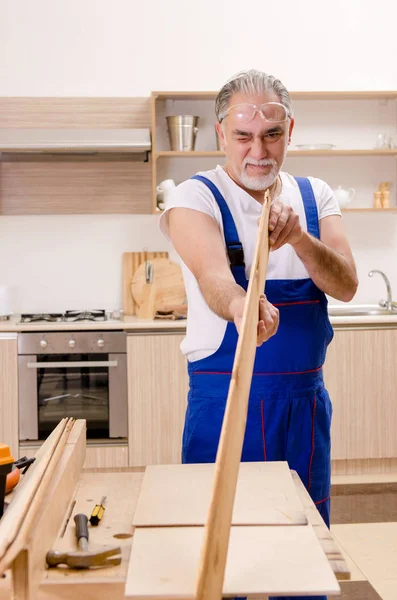 Reparador de empreiteiro envelhecido que trabalha na cozinha — Fotografia de Stock