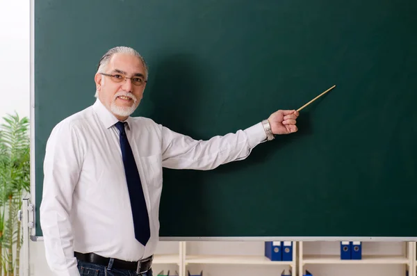 Aged male teacher in front of chalkboard — Stock Photo, Image