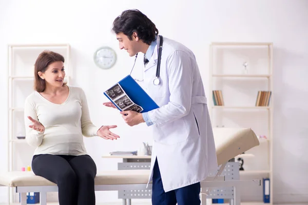 Vieille femme enceinte visitant jeune médecin masculin — Photo