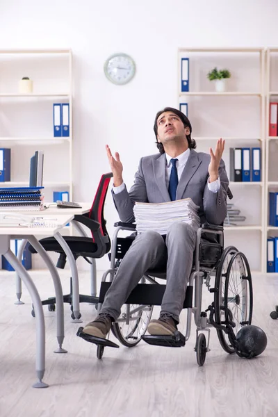 Young handsome employee in wheelchair working in the office
