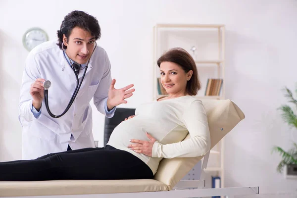 Vieille femme enceinte visitant jeune médecin masculin — Photo