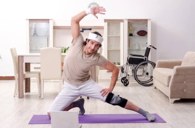 Evde egzersiz yapan yaralı genç adam. 