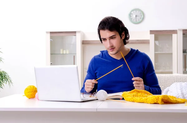 Young good looking man knitting at home