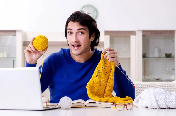 Young good looking man knitting at home