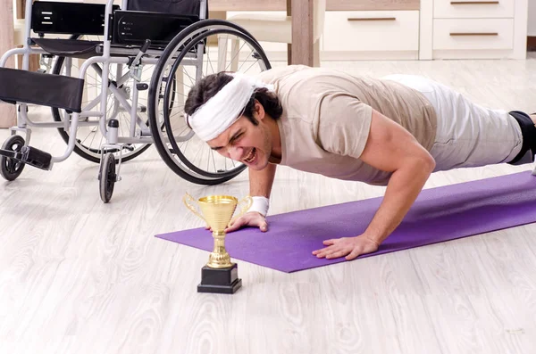 Zraněný mladý muž dělá cvičení doma — Stock fotografie