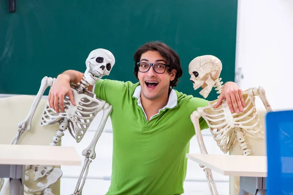 Divertido estudiante masculino en el aula con esqueleto — Foto de Stock