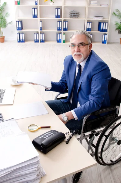 Employé âgé en fauteuil roulant travaillant au bureau — Photo