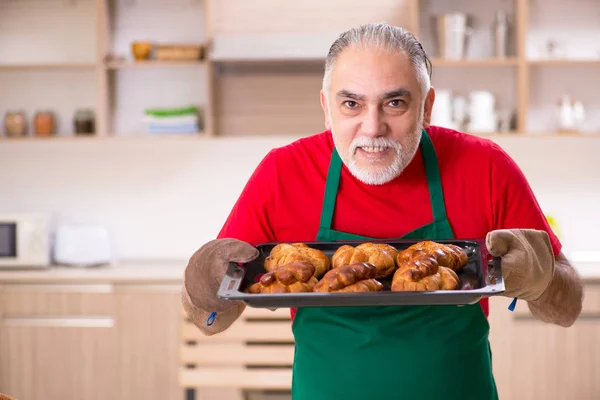 Old male baker working in the kitchen