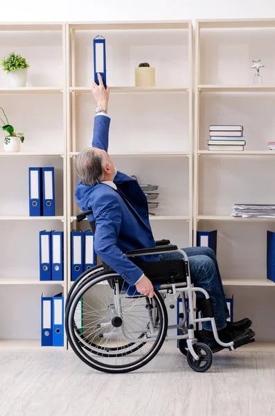 Pracownik w wieku na wózku inwalidzkim pracujący w biurze — Zdjęcie stockowe