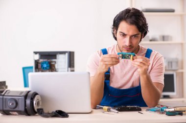 Genç bir erkek müteahhit bilgisayar tamir ediyor.  