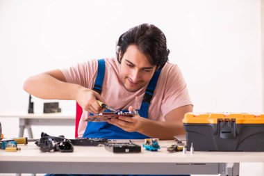 Genç bir erkek müteahhit bilgisayar tamir ediyor.  