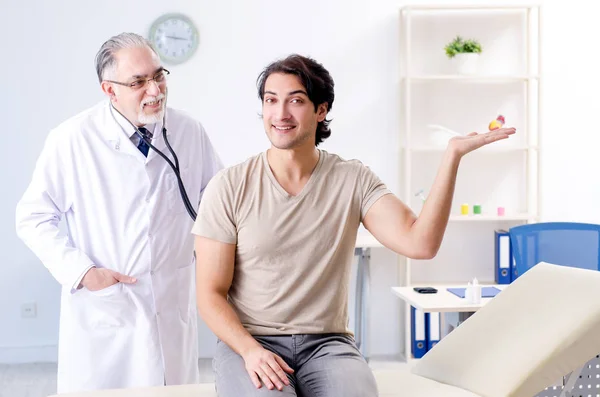 Jovem paciente do sexo masculino visitando médico velho — Fotografia de Stock