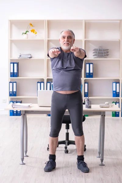 Witte baard oude man werknemer doen oefeningen in het kantoor — Stockfoto