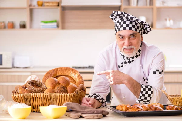 Old male baker working in the kitchen