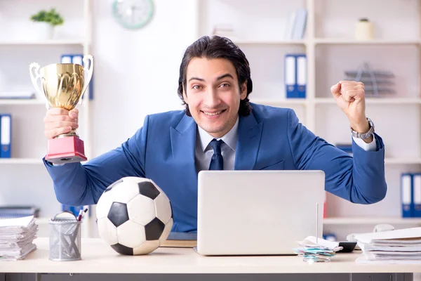Молодой привлекательный бизнесмен с футбольным мячом в офисе — стоковое фото