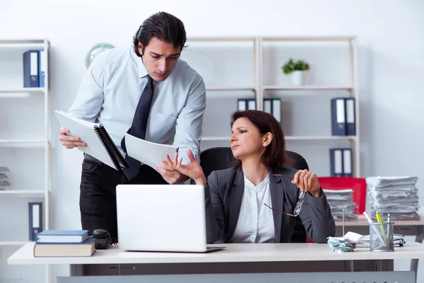 Old female boss and young male employee in the office