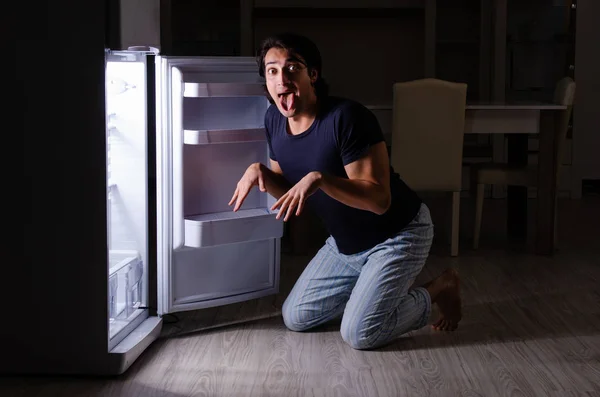 Man bryter diet på natten nära kylskåp — Stockfoto