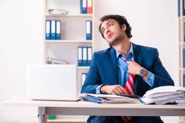 Genç yakışıklı işadamı ofiste oturuyor. 