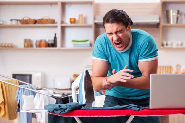 Genç adam evde çamaşır ütülüyor. 