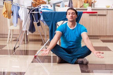 Genç adam evde çamaşır ütülüyor. 