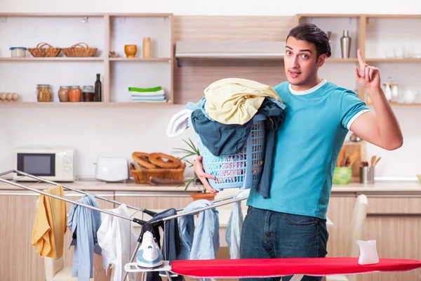 Joven marido haciendo planchado de ropa en casa — Foto de Stock