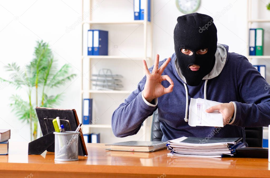 Male thief in balaclava in the office 