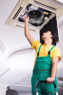 Tavan havalandırmasını tamir eden genç bir tamirci. 