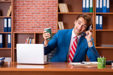 Genç yakışıklı çalışan ofiste oturuyor.  