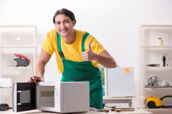 Young repairman repairing microwave in service centre — Stock Photo, Image