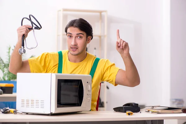 Young repairman repairing microwave in service centre — Stock Photo, Image