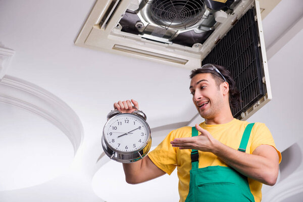 Молодой ремонтник ремонтирует потолочные кондиционеры 
