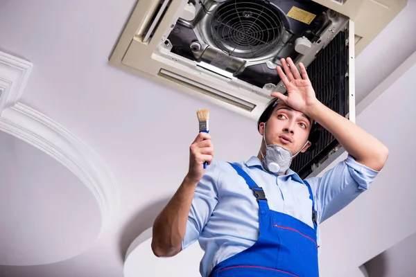 Jonge reparateur repareert airconditioning aan het plafond — Stockfoto