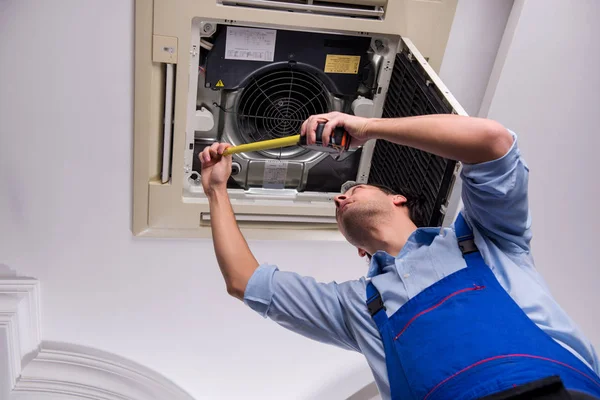 Joven reparador reparación de la unidad de aire acondicionado del techo — Foto de Stock