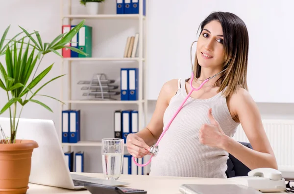 Jeune employée enceinte travaillant au bureau — Photo