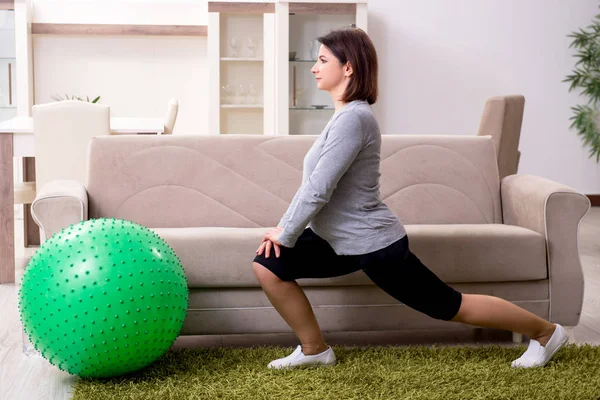 Aged pregnant woman doing exercises at home — Stock Photo, Image