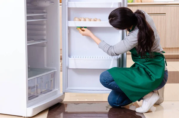 Fiatal nő takarítás hűtőszekrény higiéniai koncepció — Stock Fotó