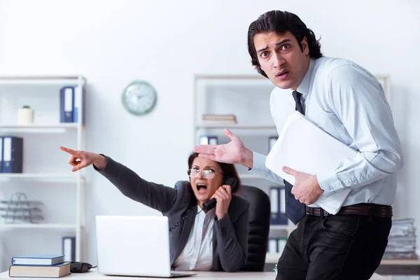 Old female boss and young male employee in the office