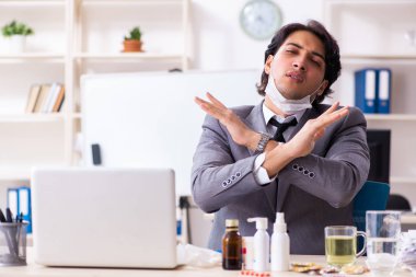 Ofiste grip olmuş bir adam çalışıyor.