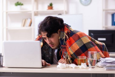 Ofiste grip olmuş bir adam çalışıyor.