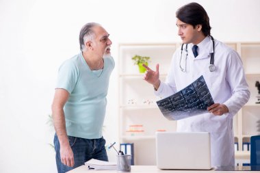 Yaşlı adam genç erkek doktoru ziyaret ediyor. 