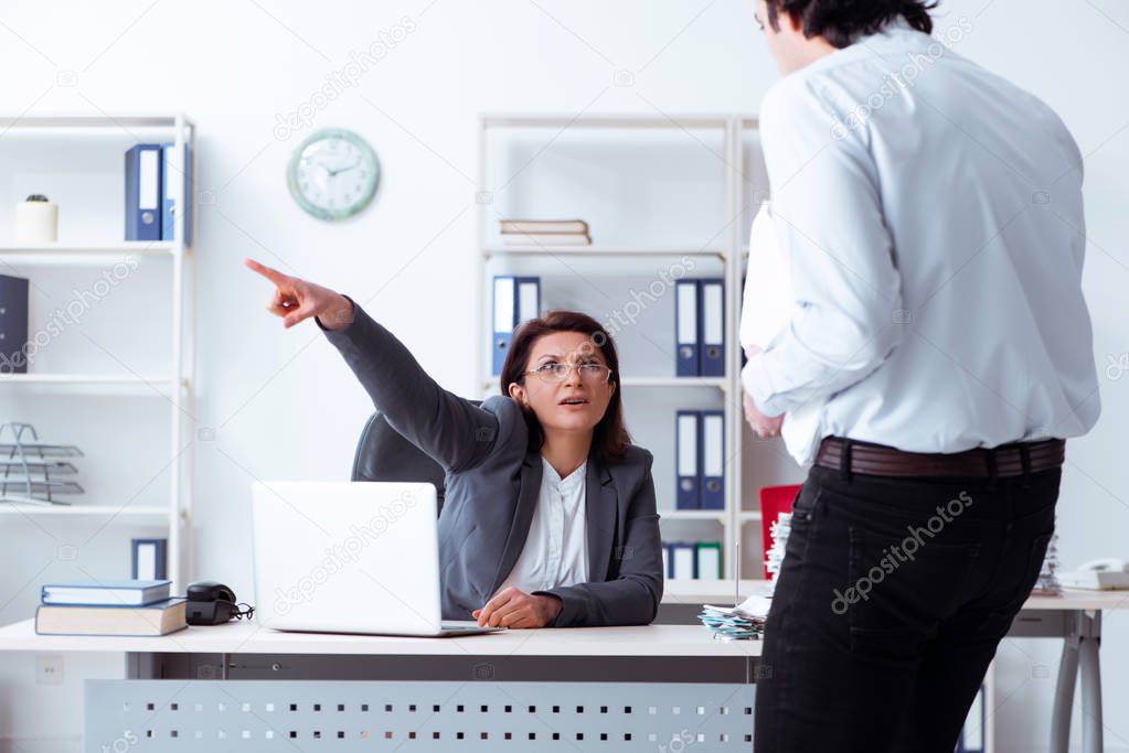 Old female boss and young male employee in the office  